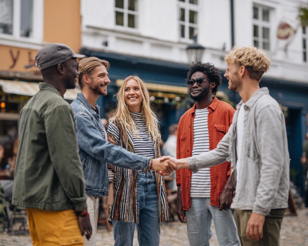 Gruppe von Menschen kommt zusammen und begrüßr sich.